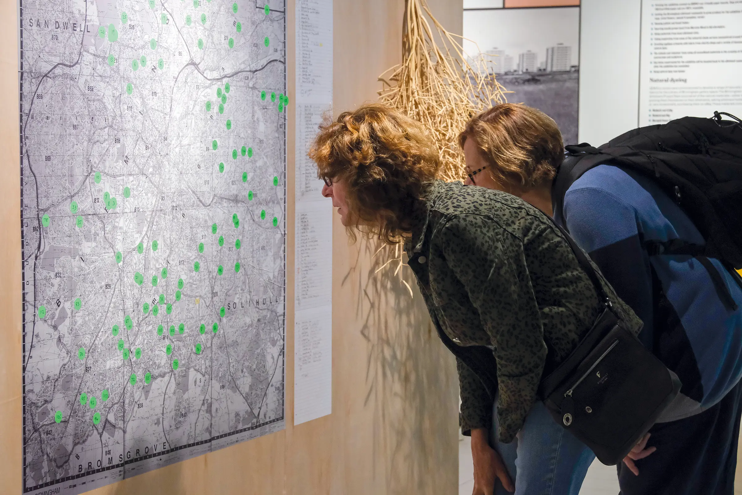 An image of two people leaning forward to look at fluorescent coloured dots on a large black and white map of Birmingham.