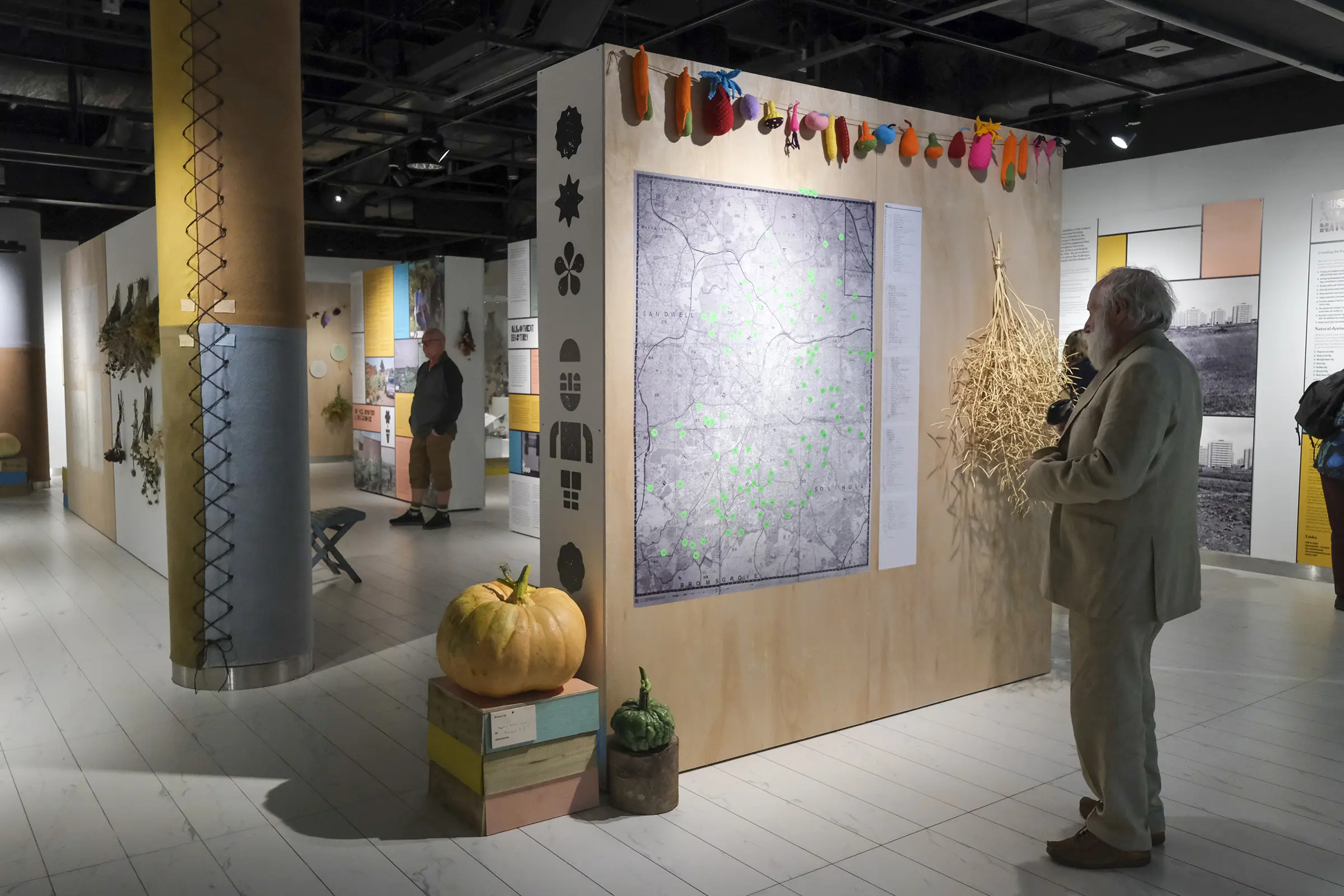 A man stands in front of an exhibition panel with a large, black and white map of Birmingham on it