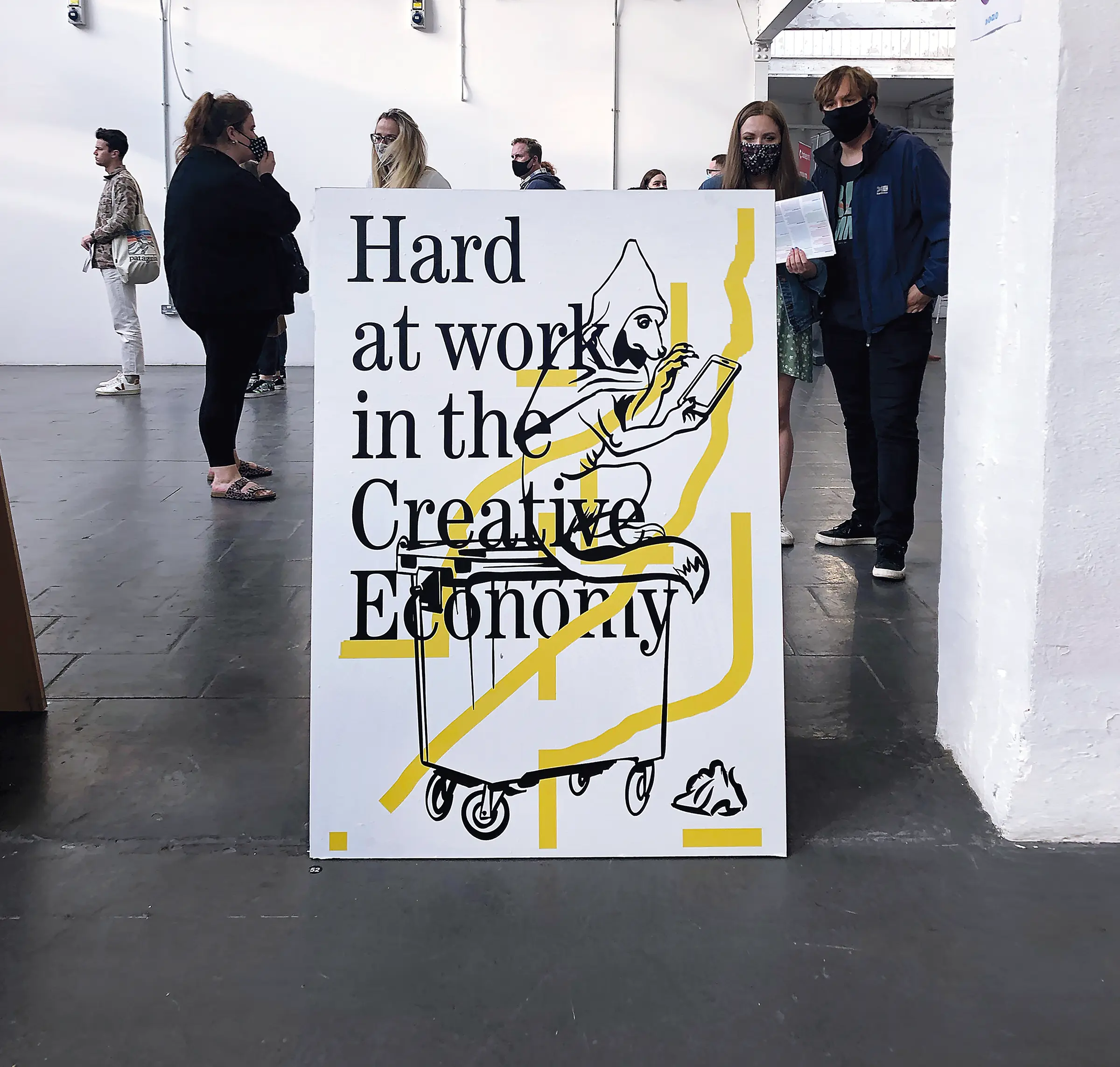 A poster featuring a line drawing of a fox sitting on a wheelie bin looking at a mobile phone, with the words 'Working hard in the creative economy' overlaid.