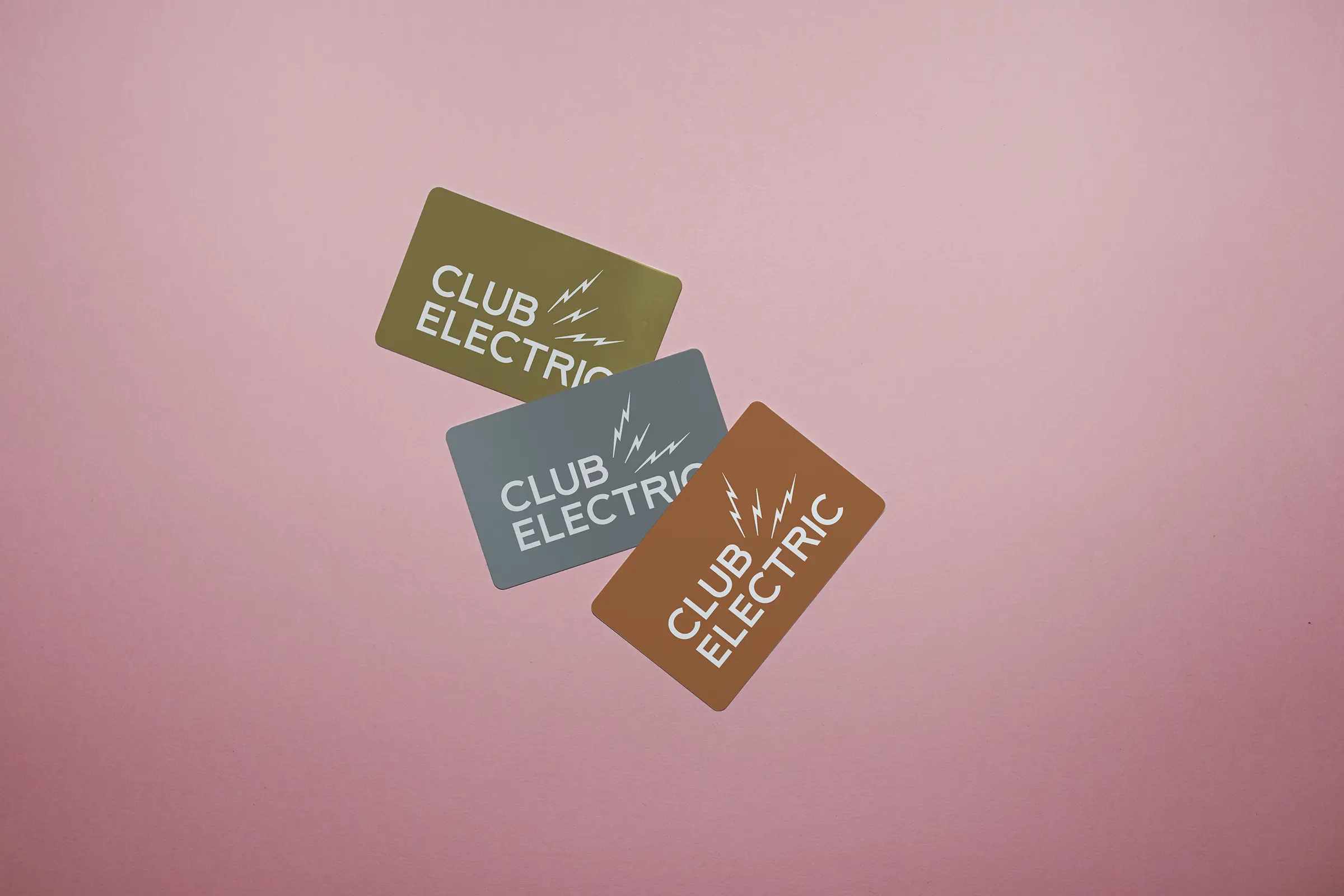 An image of gold, silver and bronze overlaid, with CLUB ELECTRIC printed in white on each.