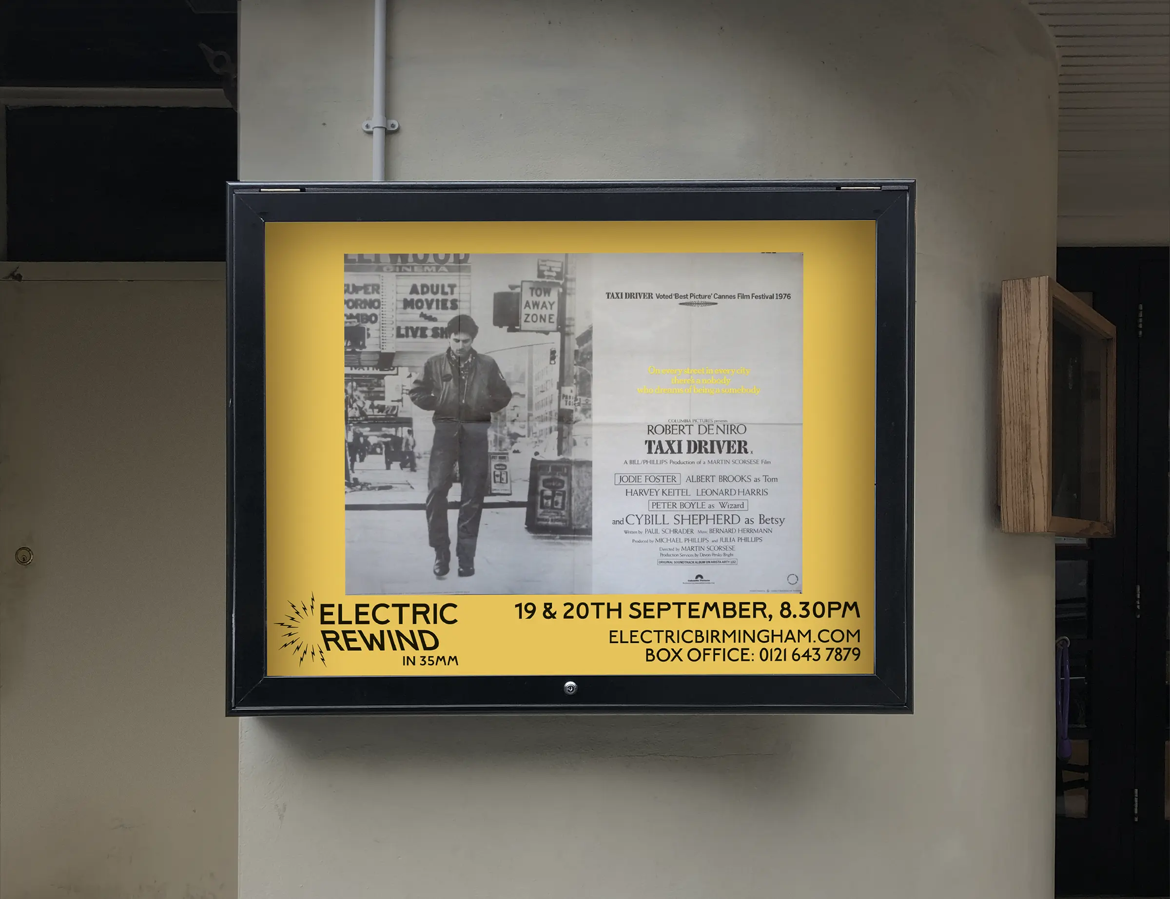 An image of a poster cabinet outside The Electric, with a bright yellow poster inside, showing the original 1970s poster for Taxi Driver, with the Electric Rewind logo and dates along the bottom. 